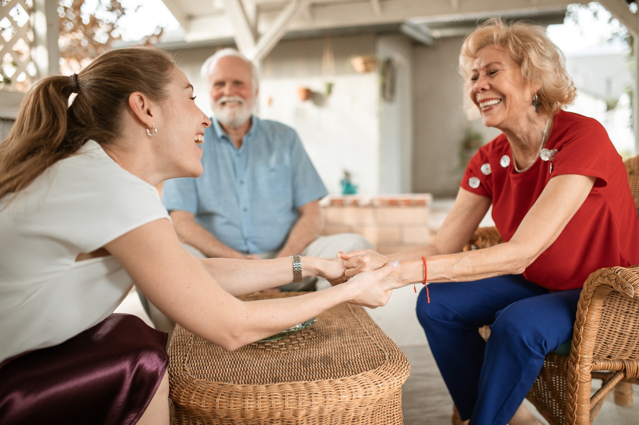 young woman and elderly couple talking and smiling