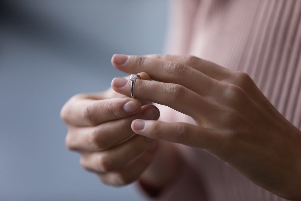 Woman taking off wedding ring after infidelity private investigation